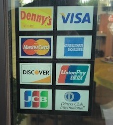 The accepted payments sticker on the front window of a Denny's diner.